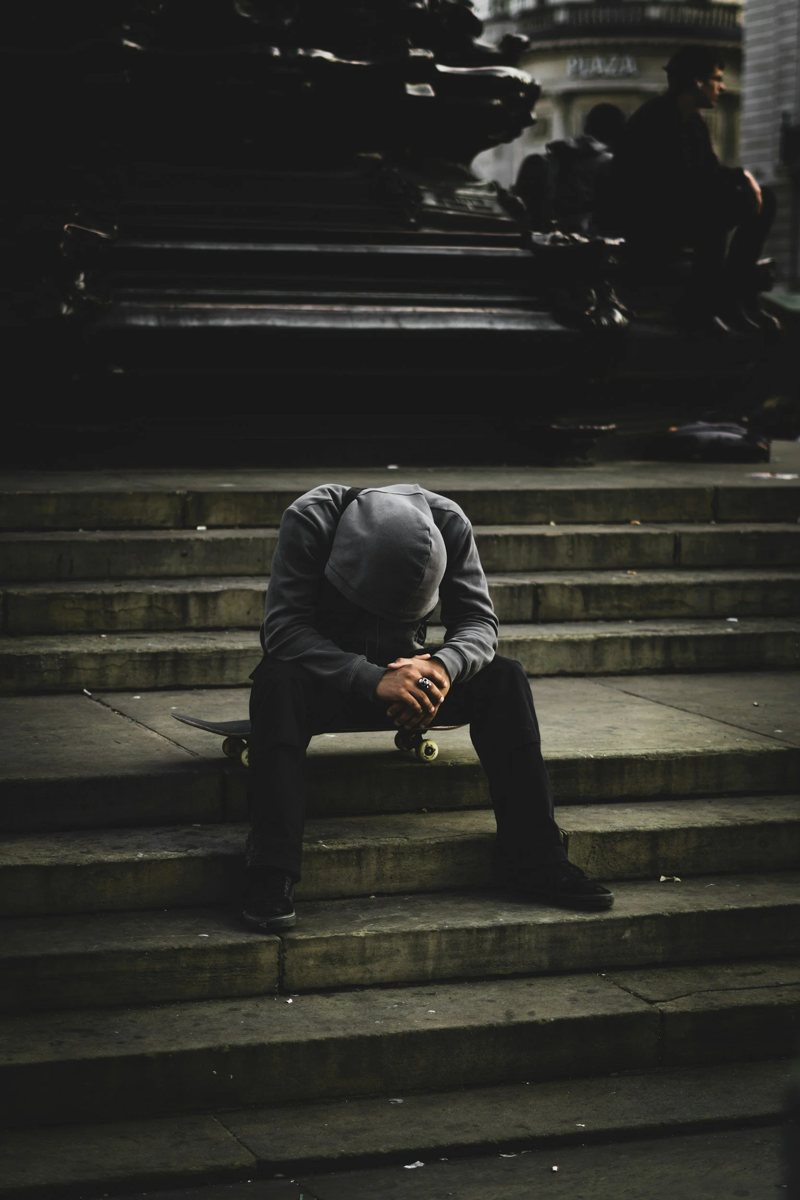 A man sitting alone on dark stairs with his head down